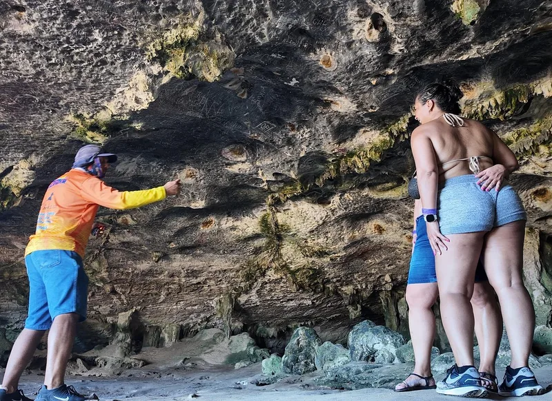 Ein Guide zeigt Gästen die Wand einer Höhle im Arikok-Nationalpark