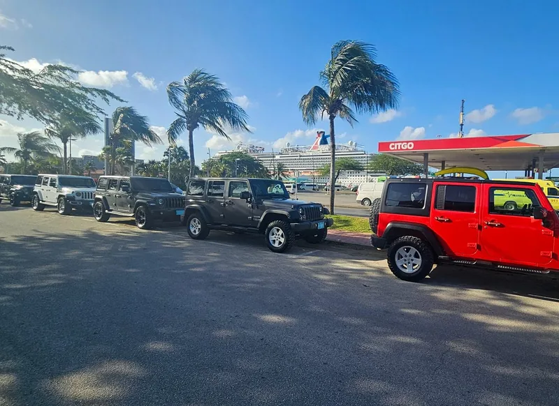 Jeep Wrangler allineate vicino al porto crociere di Oranjestad con una nave da crociera dietro